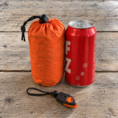 La funda del saco vivac térmico junto a una lata de refresco: ocupa menos que la lata